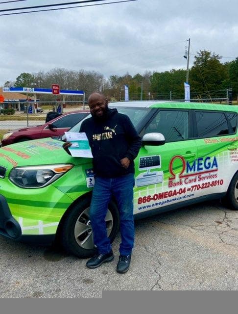 Merchant with Omega Bank Card branded vehicle wrap and rewards materials