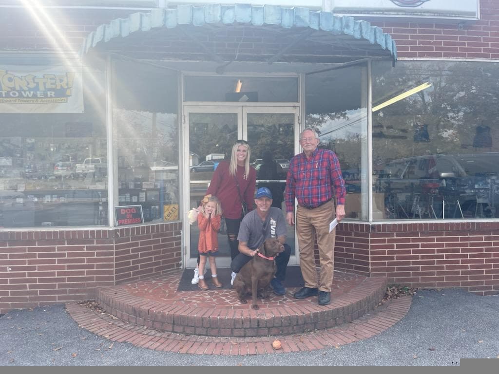 Family and team with dog in front of storefront, Omega rewards merchant partner