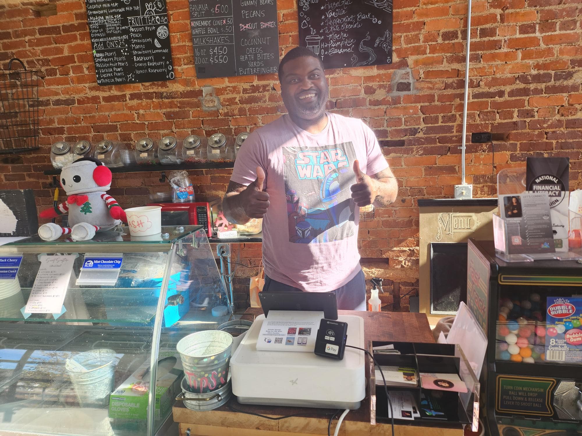 Local merchant behind counter with POS, happy with Omega rewards program